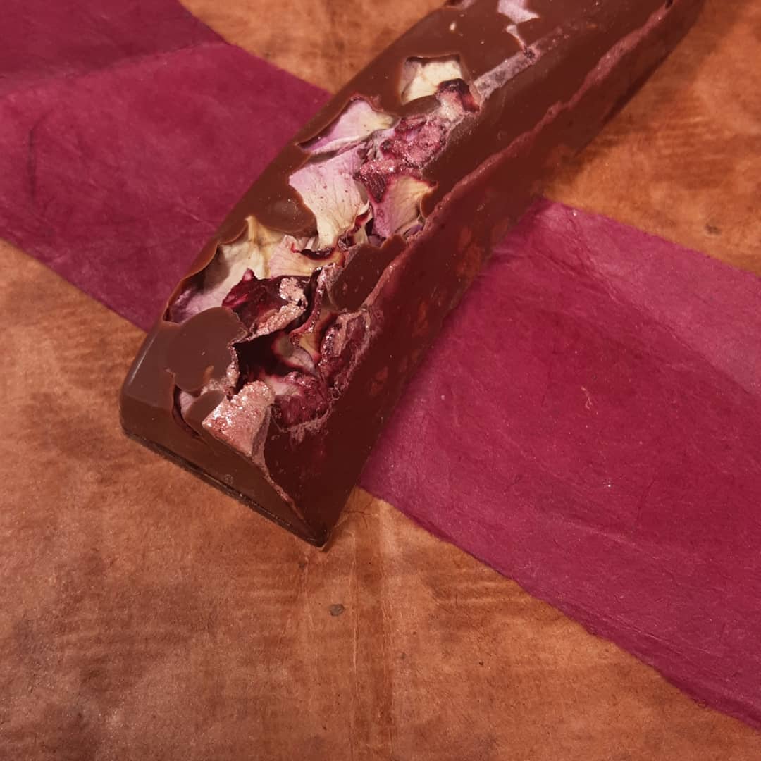LUNER ROSE: Rose and Luna Cresent Puerh ganache in a milk chocolate shell#chocolatier #rose #tea in the garden, at the waters edge, petals softly drift downstream, sunlight catches gently cresting waves, warm tea is sipped as breezes brush the brightly blooming blossoms.